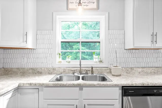 a kitchen with granite countertop white cabinets and a sink