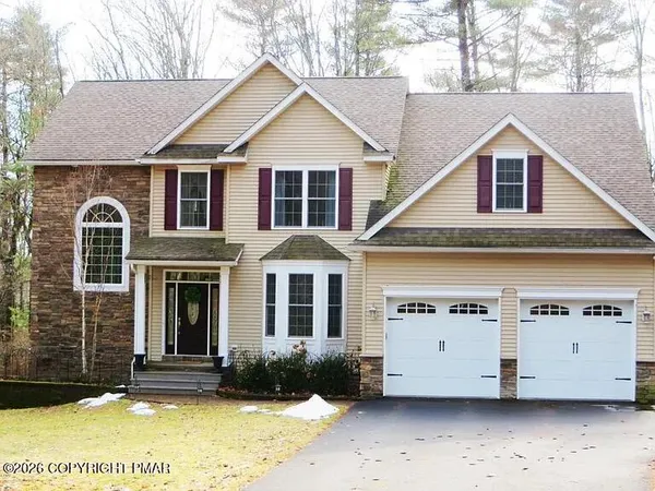 a view of a white house with large windows next to a road