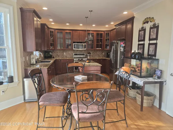 a dining room with stainless steel appliances kitchen island granite countertop a table and chairs