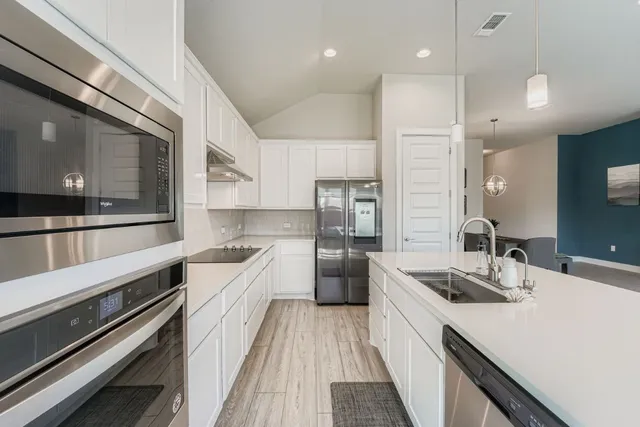 a large kitchen with stainless steel appliances a sink a stove and a refrigerator