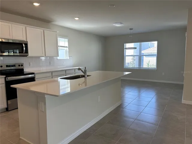 a kitchen with stainless steel appliances a sink a stove a microwave a sink a refrigerator and cabinets