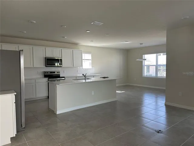 a kitchen with granite countertop a stove a sink and a refrigerator