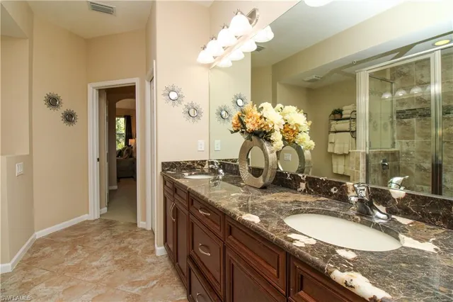 a bathroom with a granite countertop double vanity sink mirror and shower