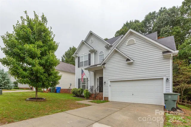 a view of a white house next to a yard with big trees