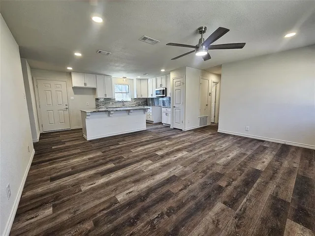 a large kitchen with kitchen island a stove a sink dishwasher and a fireplace with wooden floor