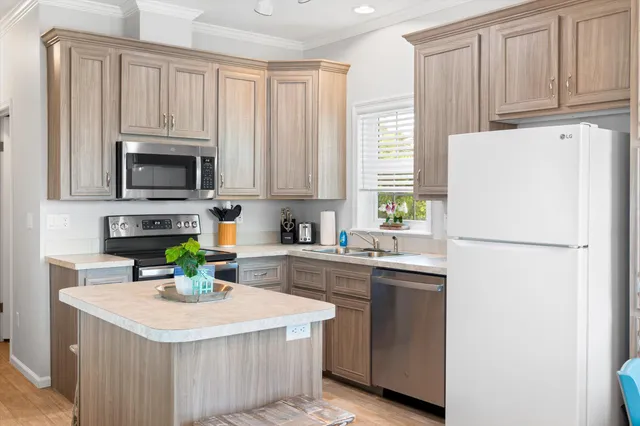 a kitchen with a refrigerator a stove a sink dishwasher a dining table and chairs with wooden floor