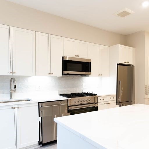 197 Green Street, Unit 303 Boston, MA 02130 - Photo 2 of 6 a kitchen with stainless steel appliances a stove a microwave and white cabinets