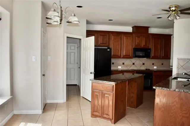 a kitchen with stainless steel appliances kitchen island granite countertop a refrigerator and a stove top oven