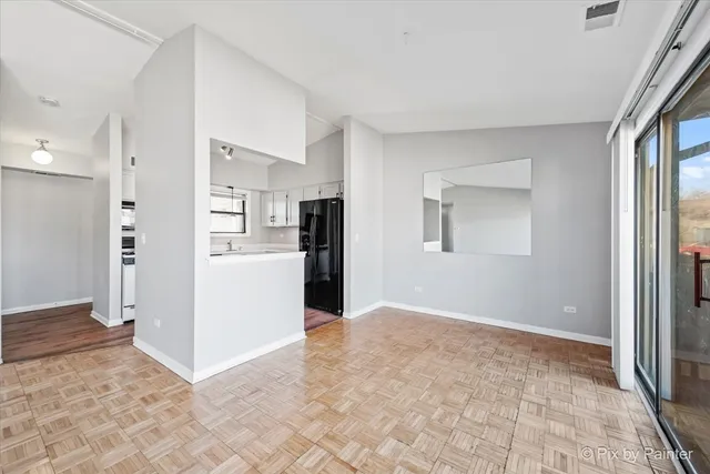 a view of a kitchen with refrigerator and white cabinets