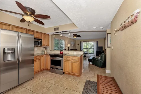 a kitchen with stainless steel appliances granite countertop a sink a stove a refrigerator cabinets and a window