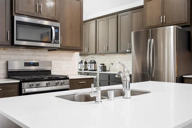 a kitchen with stainless steel appliances granite countertop a refrigerator stove top oven and sink