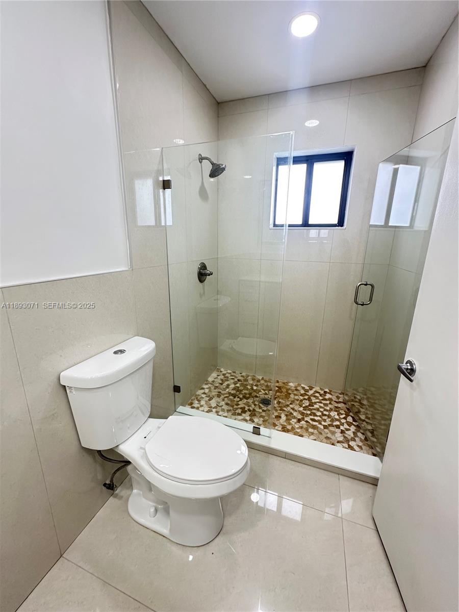 97 Northwest 73rd Place, Unit 12 Miami, FL 33126 - Photo 18 of 20 a white toilet sitting next to a bathroom sink and a shower