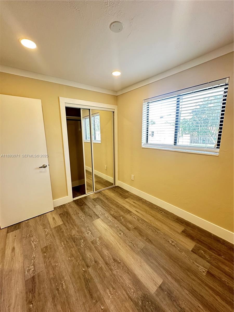 97 Northwest 73rd Place, Unit 12 Miami, FL 33126 - Photo 7 of 20 a view of an empty room with wooden floor and a window