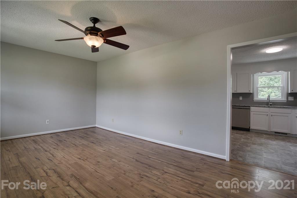 2345 Sides Road Rockwell, NC 28138 - Photo 3 of 19 an empty room with wooden floor a ceiling fan and kitchen view