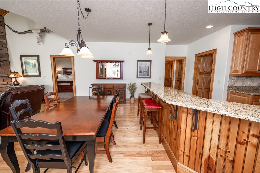 311 Penny Lane, Unit 2D Banner Elk, NC 28604 - Photo 5 of 38 a dining room with wooden floor a chandelier a wooden table and chairs