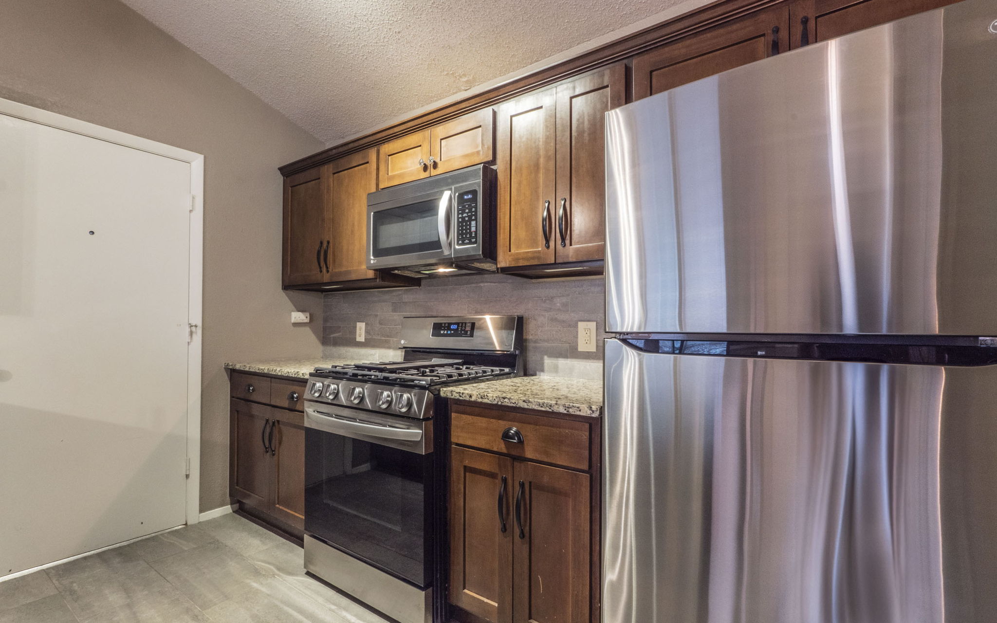 1007 Markham Lane, Unit A Austin, TX 78753 - Photo 3 of 15 a kitchen with stainless steel appliances granite countertop a refrigerator a stove and a sink