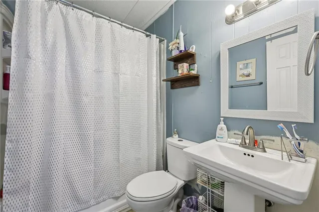 a bathroom with a sink a toilet and shower curtain