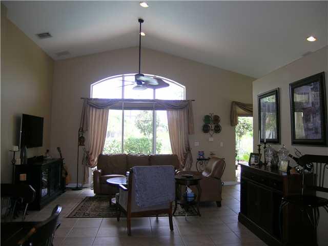 2927 Southeast Racoon Way Stuart, FL 34997 - Photo 3 of 22 a living room with furniture a chandelier a large window and a flat screen tv