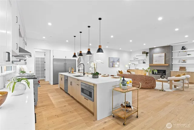 a kitchen with stainless steel appliances granite countertop a stove top oven a sink dishwasher and white cabinets with wooden floor