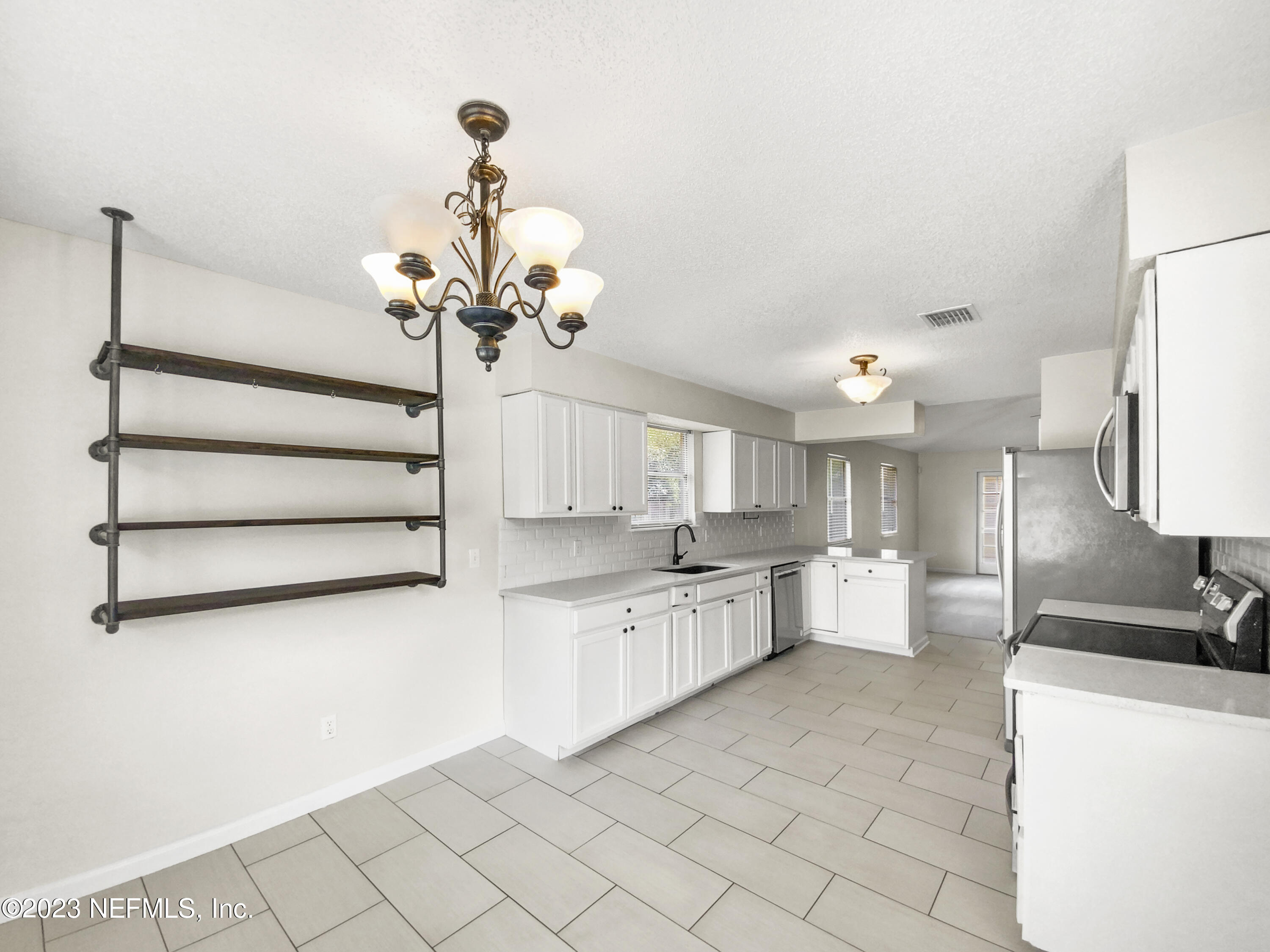 3550 Loretto Road Jacksonville, FL 32223 - Photo 9 of 19 a kitchen with white cabinets and chandelier