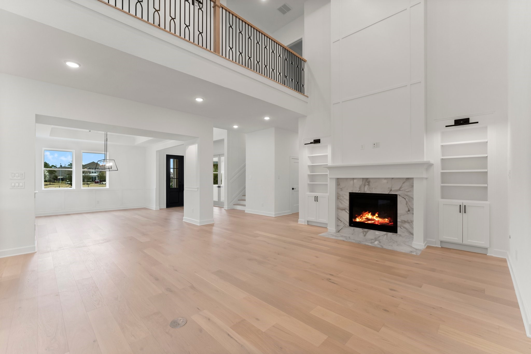 7315 Julie Pond Lane Spring, TX 77389 - Photo 6 of 48 This spacious living area features high ceilings, a modern fireplace with a marble surround, light wood flooring, and built-in shelves.