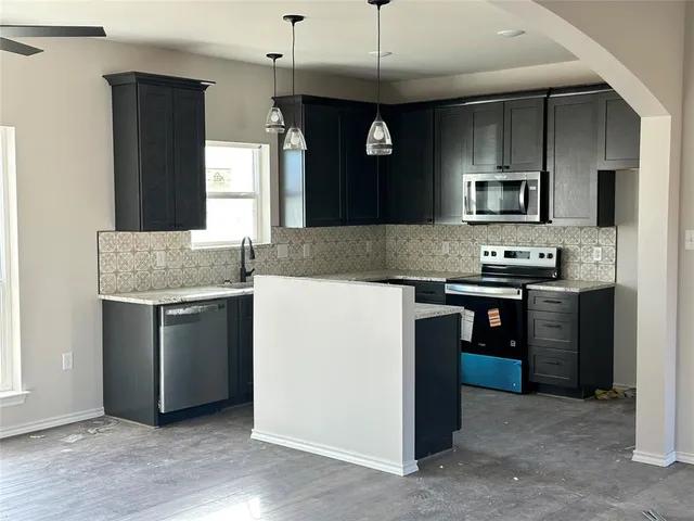 a kitchen with kitchen island granite countertop stainless steel appliances a sink stove and refrigerator