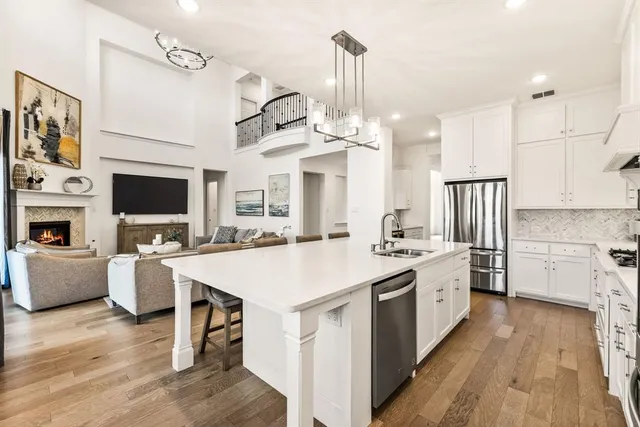 a large kitchen with stainless steel appliances a stove a sink dishwasher a oven and a dining table with wooden floor