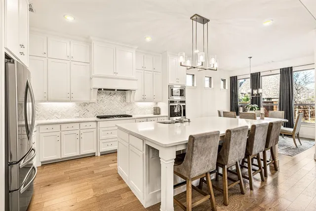 a kitchen with stainless steel appliances kitchen island granite countertop a table chairs stove and cabinets