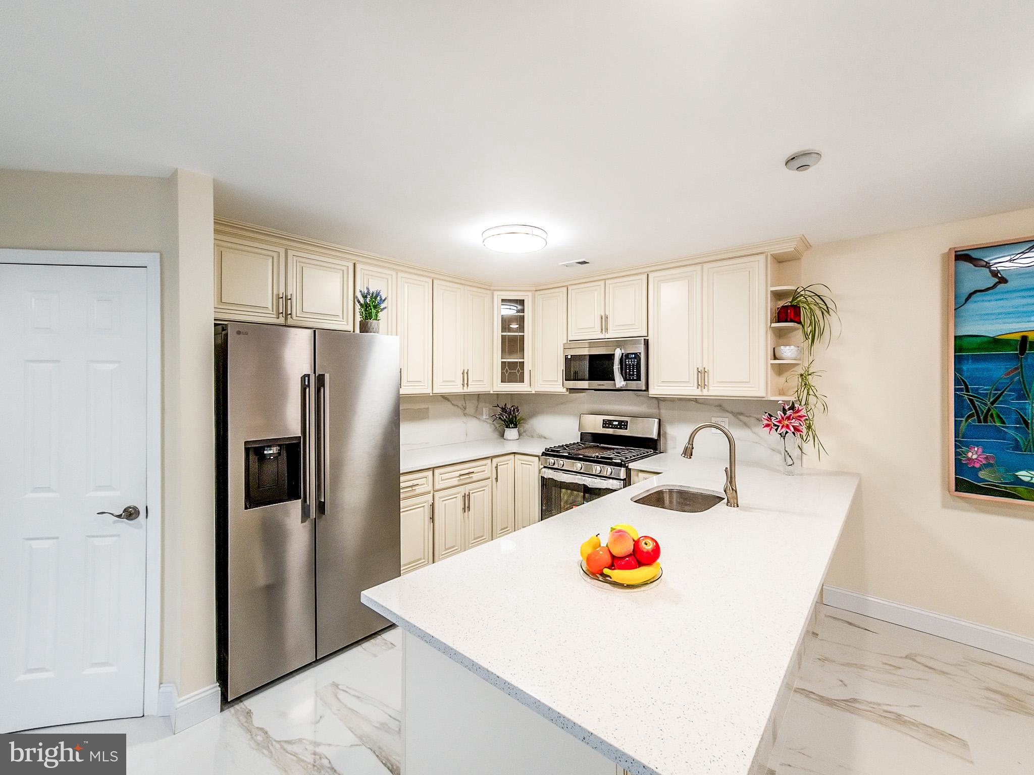 7 C Rutland Lane Monroe Township, NJ 08831 - Photo 25 of 41 a kitchen with stainless steel appliances granite countertop a refrigerator a stove a sink a dining table and chairs with wooden floor