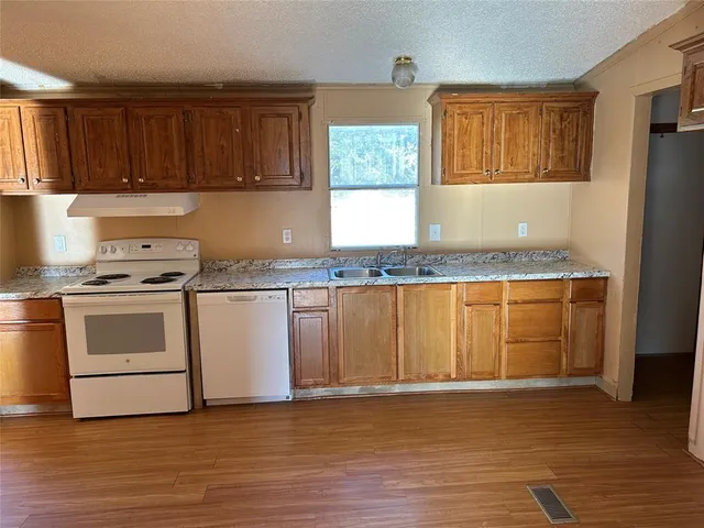 a kitchen with granite countertop white cabinets and white appliances