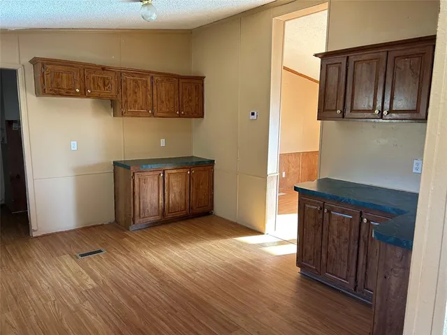 a view of an empty room with wooden floor and cabinet