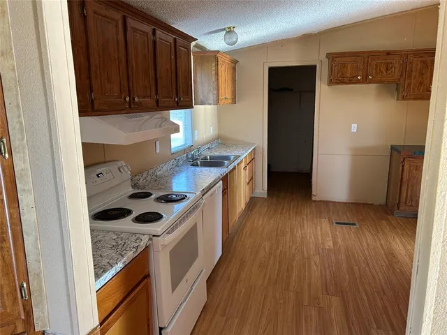 a kitchen with a hard wood floor white cabinets and stainless steel appliances