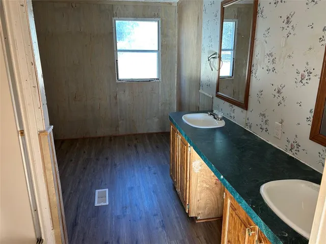 a bathroom with a sink a mirror and wooden floor