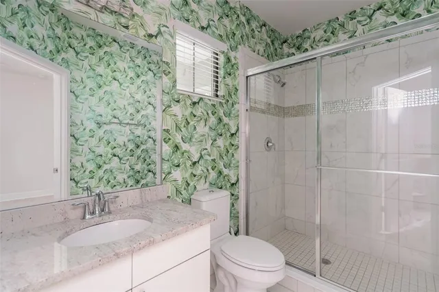 a bathroom with a granite countertop sink a toilet and shower