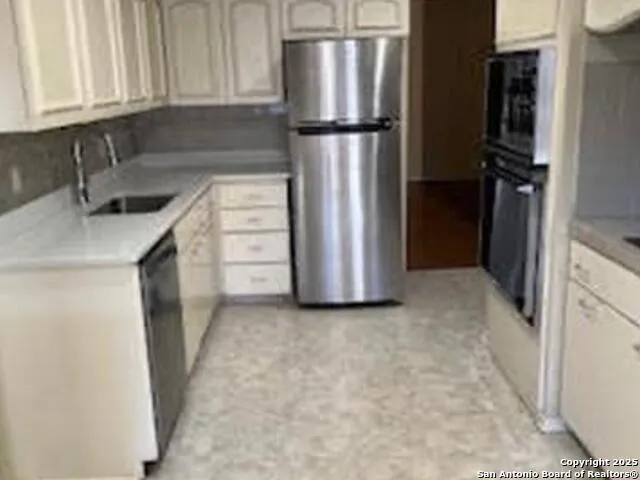 a kitchen with a refrigerator sink and cabinets