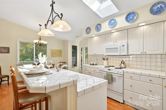 a kitchen with a stove a chandelier and a view of living room