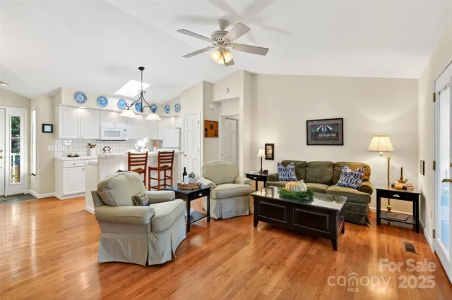 a living room with furniture kitchen view and a chandelier