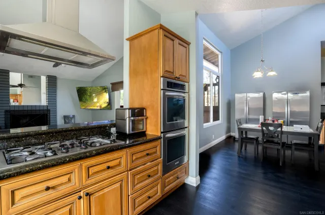 a kitchen with stainless steel appliances granite countertop a stove and a view of living room