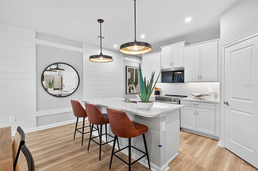 8838 Ginko Run Parrish, FL 34219 - Photo 5 of 21 a kitchen with stainless steel appliances granite countertop a dining table chairs refrigerator and cabinets