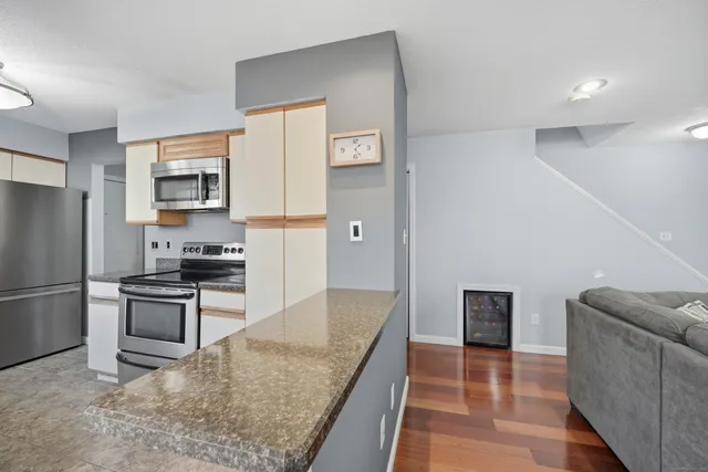a kitchen with granite countertop a refrigerator and a stove top oven