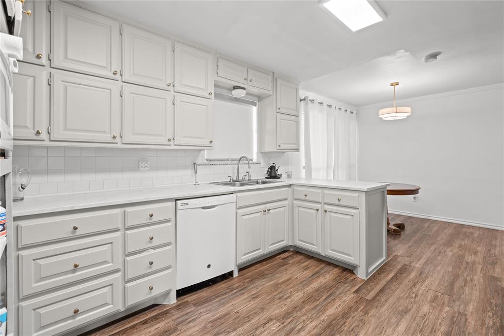 3506 Ruidoso Drive Arlington, TX 76017 - Photo 15 of 37 Kitchen featuring extensive white cabinetry, white subway tile backsplash, light-toned countertops, and wood-finish flooring
