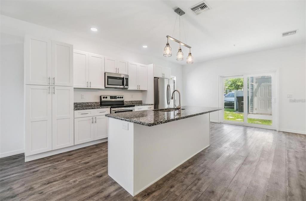 1264 Pierce Street Clearwater, FL 33756 - Photo 2 of 16 a large kitchen with granite countertop a stove top oven a sink a counter space and cabinets
