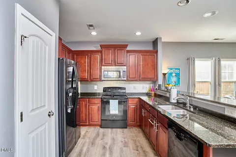 a kitchen with stainless steel appliances granite countertop a stove a sink dishwasher a refrigerator and a wooden cabinets
