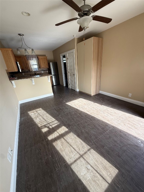 1313 Delano Street Austin, TX 78721 - Photo 32 of 32 Kitchen with stainless steel appliances, open floor plan, brown cabinetry, a breakfast bar, and a peninsula