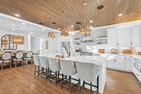 a kitchen with stainless steel appliances kitchen island granite countertop a dining table chairs and view living room