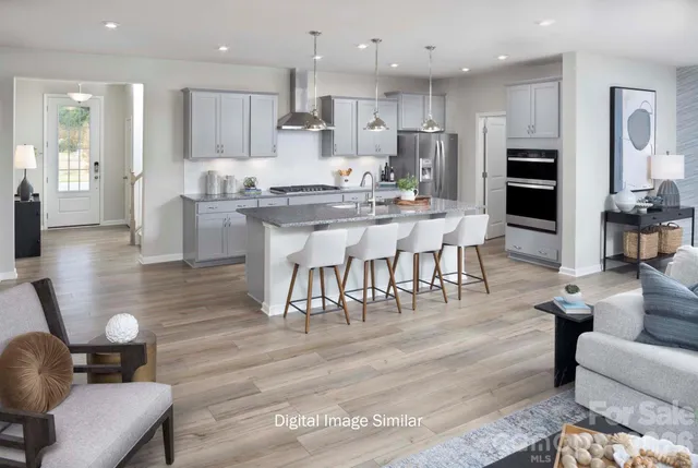 a kitchen with stainless steel appliances kitchen island granite countertop a table chairs and a living room view