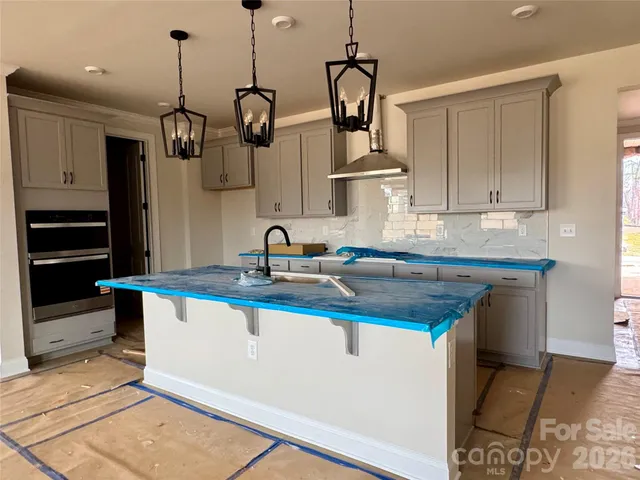 a kitchen with stainless steel appliances granite countertop a sink a stove and a wooden floors