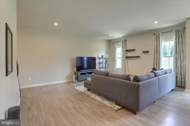 a living room with furniture a flat screen tv and a refrigerator