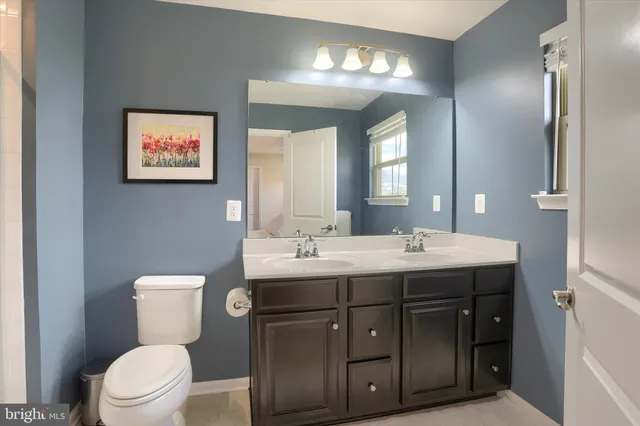 a bathroom with a granite countertop sink mirror vanity and toilet