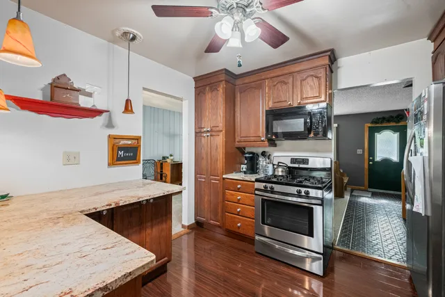 a kitchen with stainless steel appliances kitchen island granite countertop a stove and a wooden floor